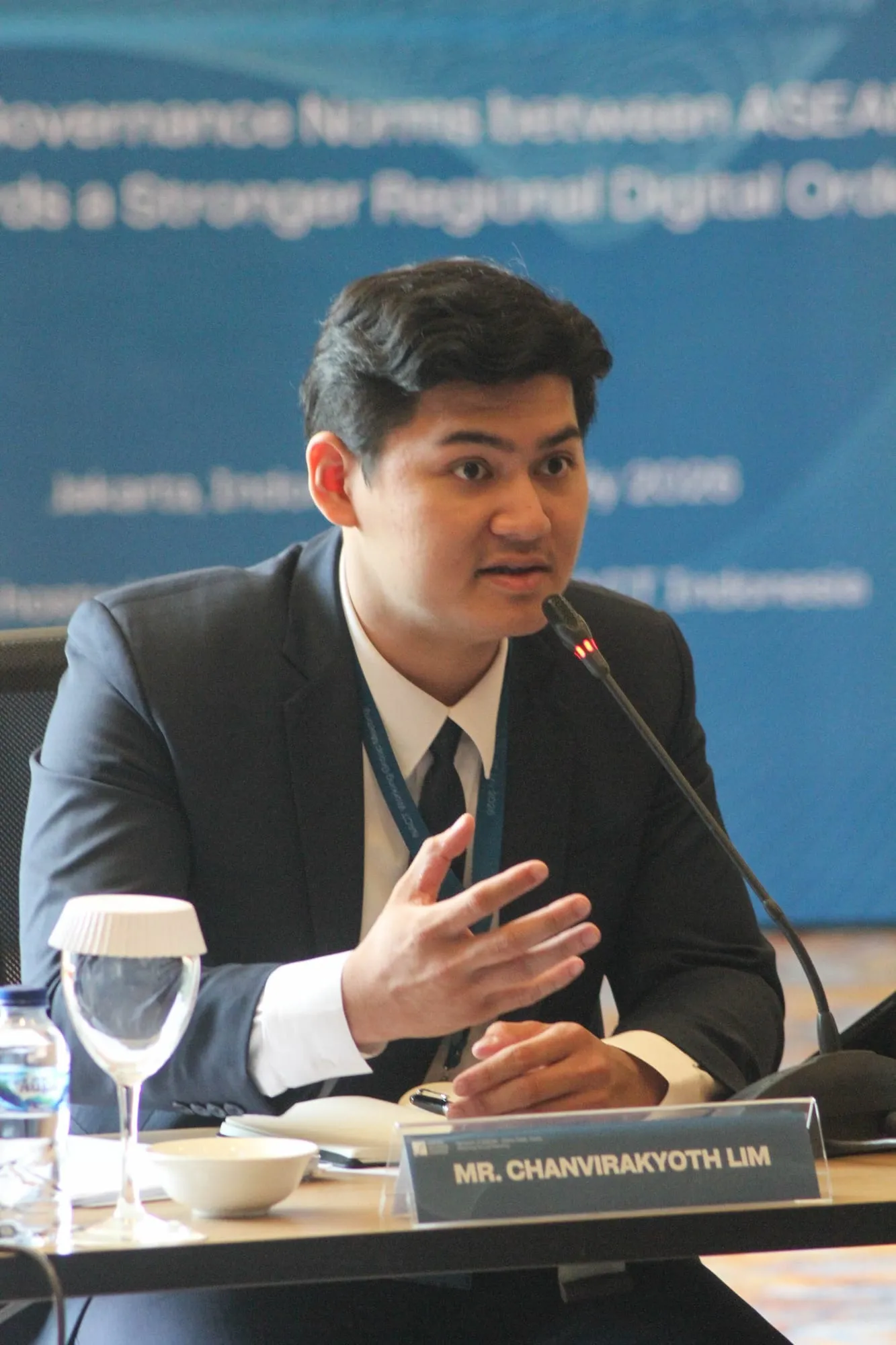 Close-up of Lim Chanvirakyoth explaining a point with an open hand at the microphone