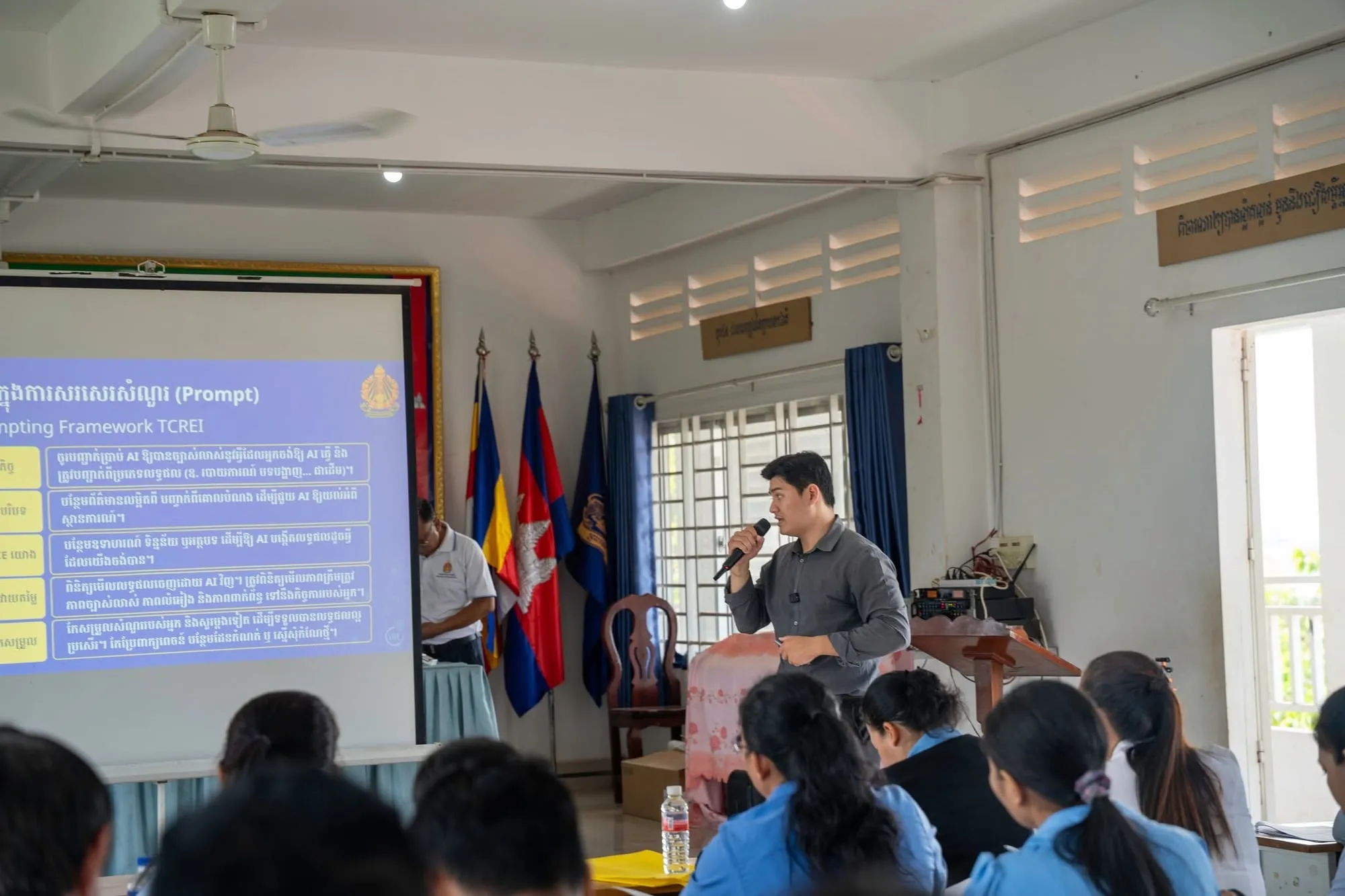 Lim Chanvirakyoth speaking with a microphone beside a slide about prompts