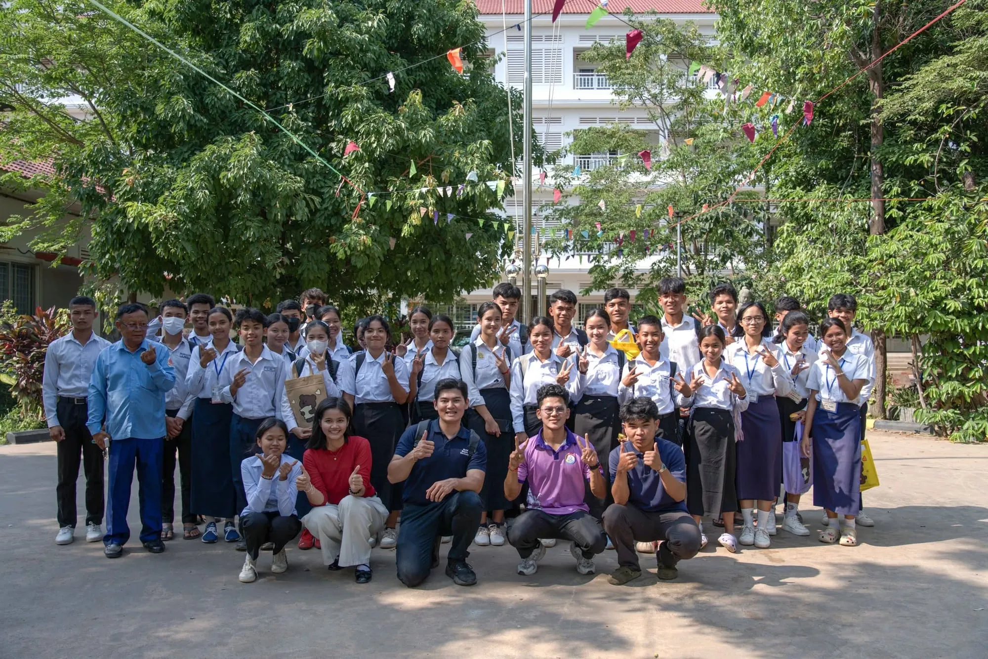 Group photo of students and trainers outdoors in the schoolyard